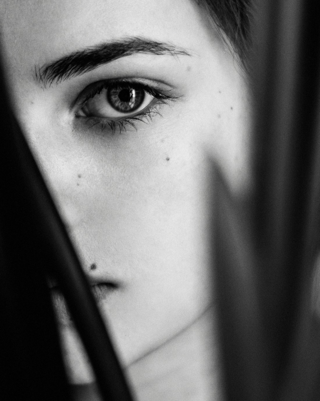 Close black-and-white portrait of a woman's eye and skin in soft light